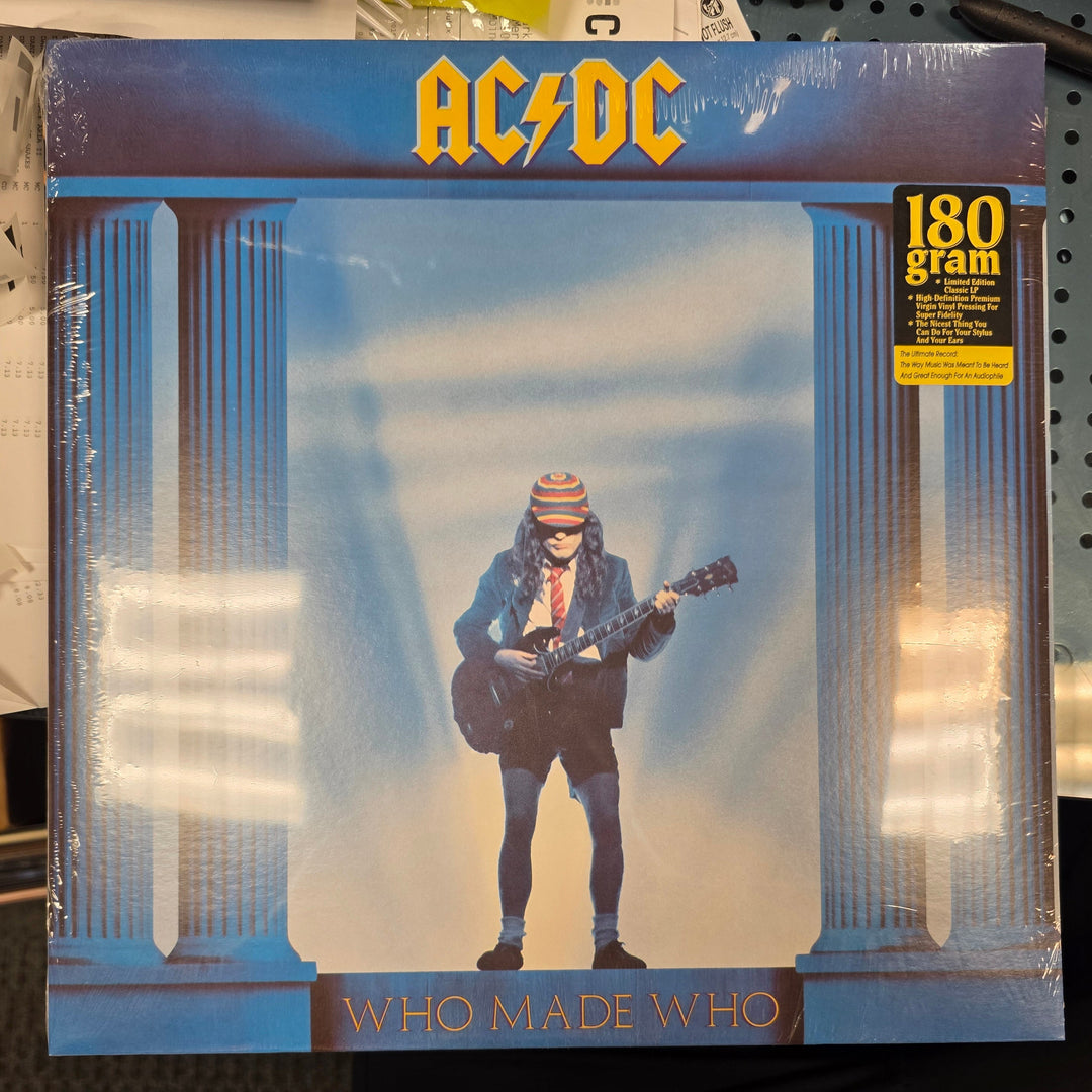Vinyl record cover for AC/DC's 'Who Made Who' with a person playing guitar on a blue background.