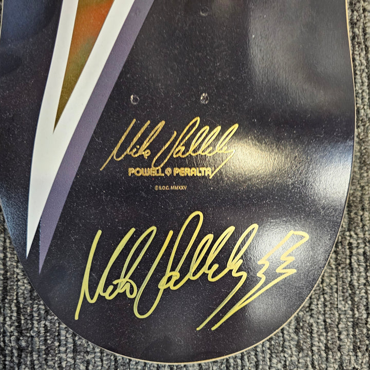 Mike Vallely signed skateboard deck with gold signature and text on a textured gray surface