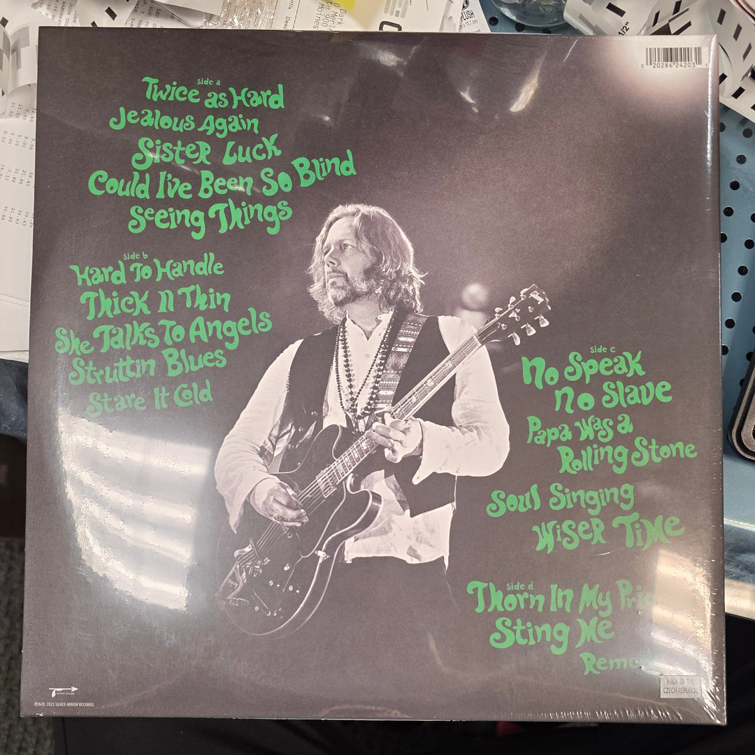 Vinyl record with a cover featuring a guitarist and text on a table.