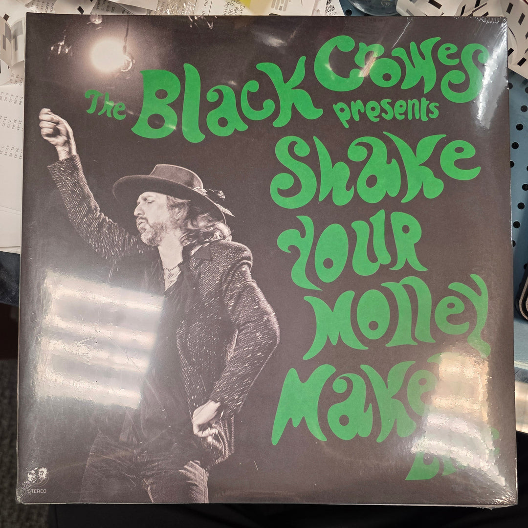 Vinyl record cover with green text and black and white illustration on a table.